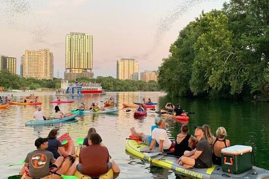 Paddleboarders watching the bats on Lady Bird Lake during sunset.